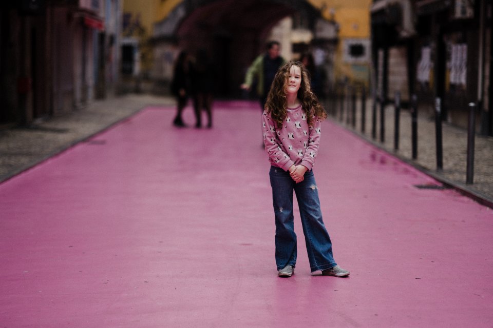 A young girl in jeans and a pink top standing on a pink road